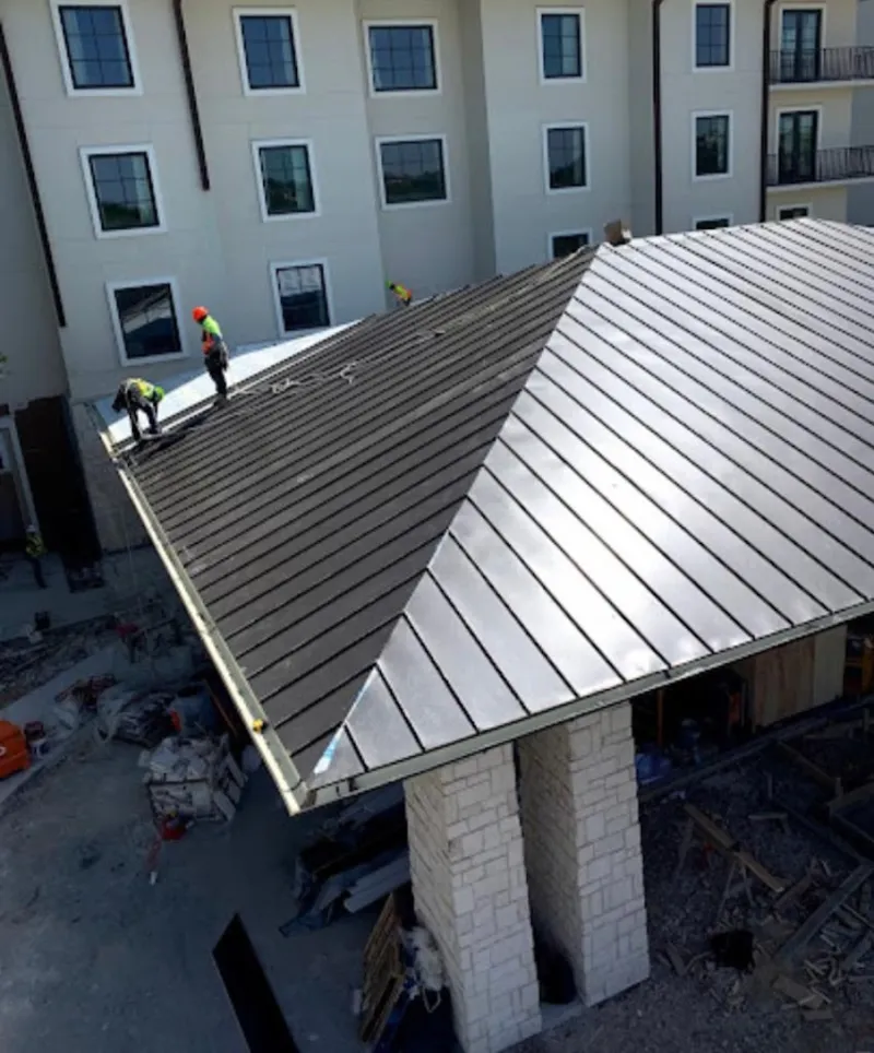 Crew installing standing seam metal roof panels on a commercial project in Cortez